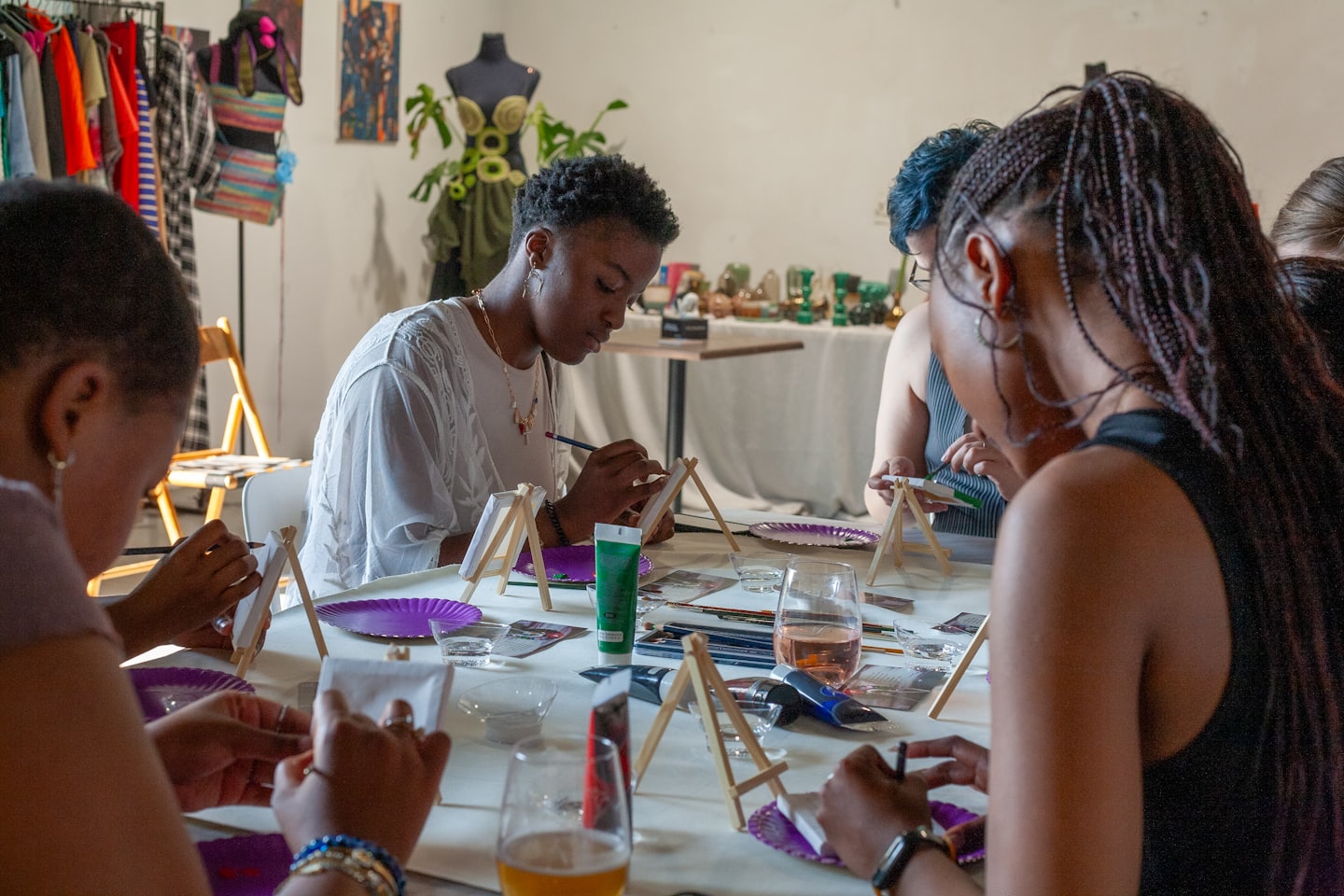 Diverse group of people painting canvases at an art workshop table.