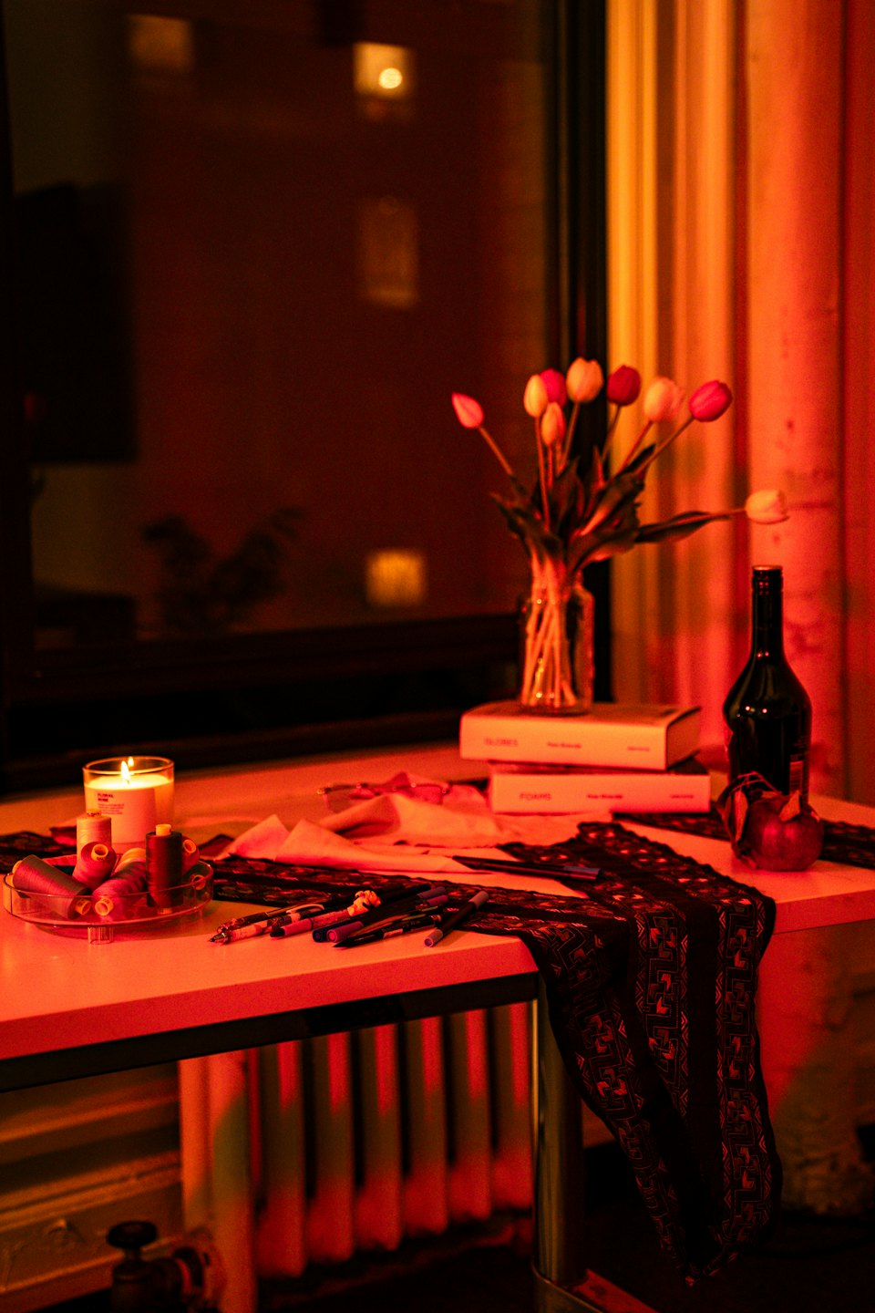 Craft supplies and a lit candle sit on a table.